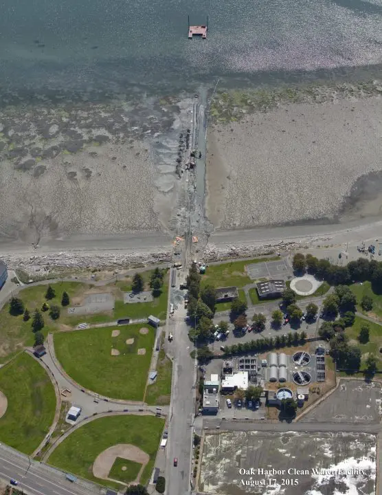 Aerial view of a coastal area with a park, water facility, and construction near the shore.