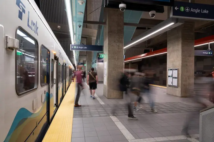Train at Angle Lake station with passengers moving on platform, capturing transit hustle and urban commuting.