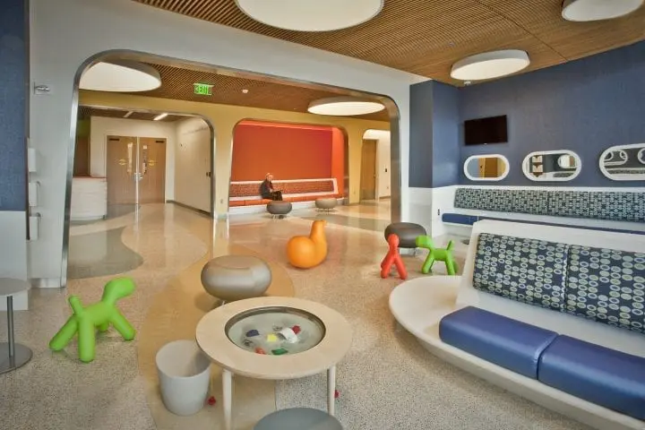 Modern hospital waiting area with colorful furniture and playful sculptures, designed for comfort and a welcoming atmosphere.