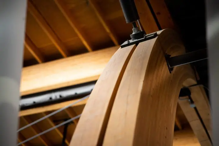 Curved wooden beam architecture detail with metal support in a modern building, showcasing craftsmanship and structural design.