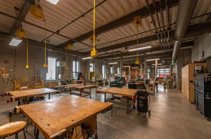 Spacious woodworking workshop with various tools, workbenches, and organized equipment, offering a creative maker space ambiance.