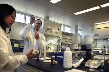 Scientists in a modern lab conducting experiments with pipettes and lab equipment.