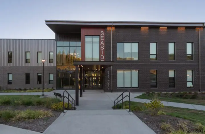Modern brick building with large windows labeled Seaside and a landscaped entrance at 2600 Spruce.