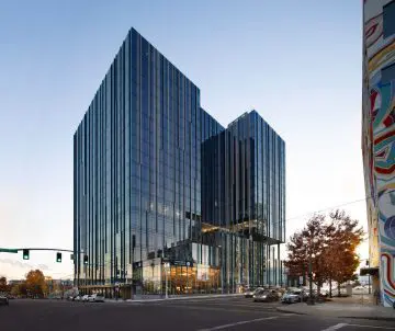 Modern glass office building with a sleek design at a city intersection during sunset. Urban architecture and street view.