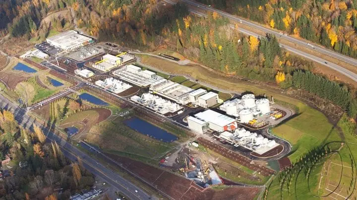 Aerial view of a water treatment plant surrounded by trees and roads, highlighting modern infrastructure in a natural setting.