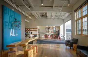 Modern bike-friendly office space with wooden furniture, bicycles, and large windows offering scenic views.