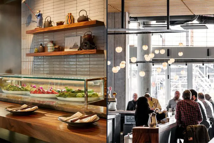 Modern restaurant interior with wooden shelves, sushi display, and patrons sitting at a bar with overhead globe lights.