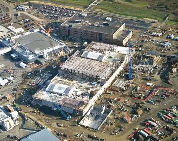 Aerial view of a large construction site with cranes and buildings underway, showcasing industrial development progress.