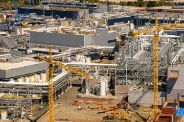 Aerial view of a large industrial complex with cranes, structures, and machinery, highlighting construction and development activity.