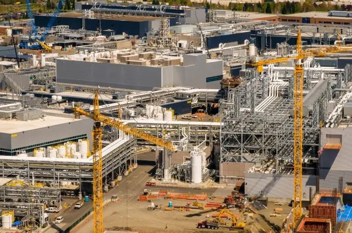 Aerial view of a large industrial complex with cranes, structures, and machinery, highlighting construction and development activity.