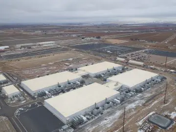 Aerial view of a large data center surrounded by fields in a winter landscape, showcasing modern infrastructure and remote location.
