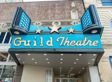 Guild Theatre entrance with stylish marquee sign, featuring neon lights and stars. Vintage cinema vibes in urban setting.