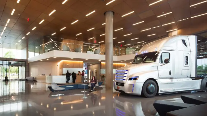 Futuristic semi-truck displayed in a modern office lobby with sleek design elements and ambient lighting.