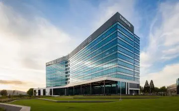 Modern glass office building of Daimler at sunset, featuring sleek architecture and lush green surroundings.