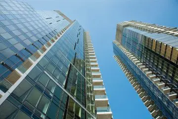 Modern skyscrapers with glass facades soaring into a clear blue sky, highlighting urban architecture and vertical design.