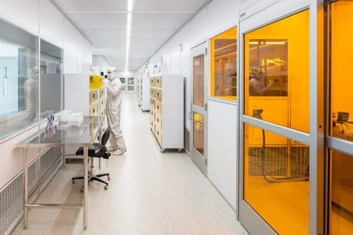 Technician in cleanroom attire works in a high-tech laboratory, focusing on precise tasks under controlled conditions.