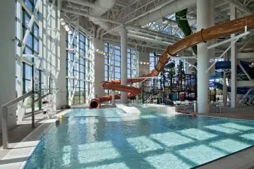 Indoor water park with a large waterslide and clear pool under bright natural light. Spacious area for recreational activities.