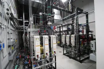 Industrial room with complex piping, control panels, and valves for machinery systems and maintenance.