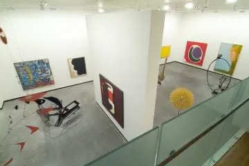 Contemporary art gallery with abstract paintings and sculptures on display, featuring diverse forms and vivid colors.
