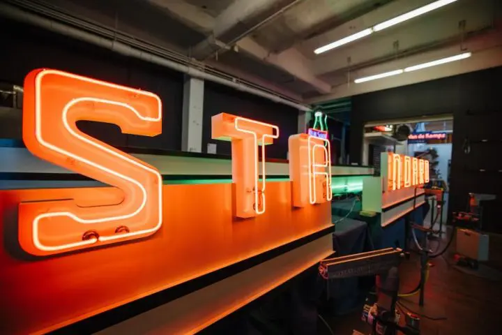 Neon letters STA glowing in a workshop, showcasing vibrant signage design.