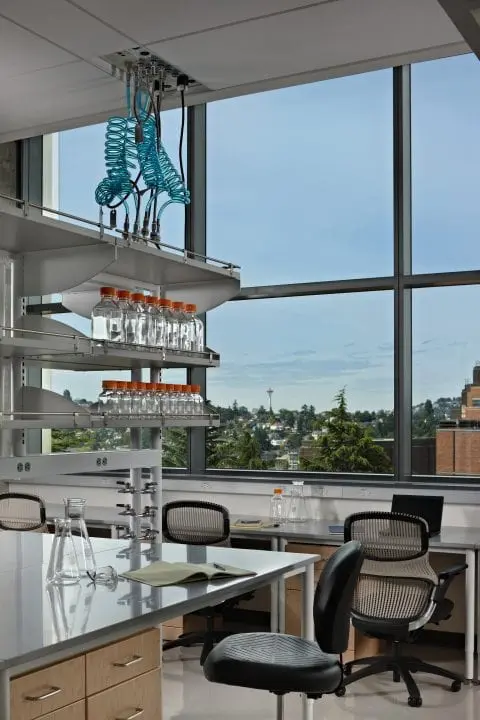 Modern laboratory with glassware, desks, and window view of cityscape; bright and organized workspace environment.