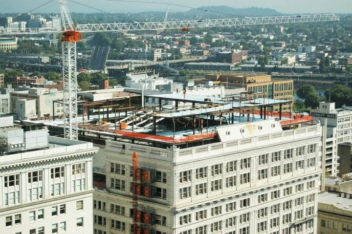 Urban construction site with crane atop a city building, surrounded by a sprawling cityscape.