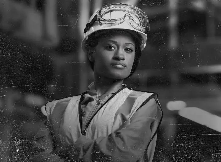 Confident construction worker wearing a hard hat and safety vest, striking a determined pose.
