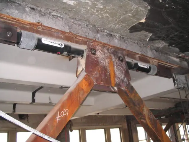 Rustic metal beam with turnbuckle tensioners supports an industrial construction site ceiling.