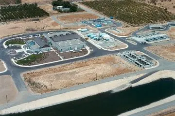 Aerial view of a water treatment facility surrounded by fields, showcasing infrastructure and storage tanks.