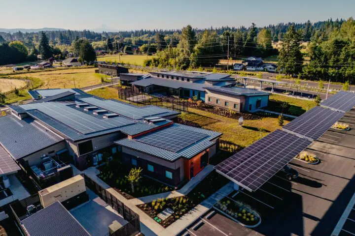 Aerial view of modern buildings with solar panels in a scenic, rural setting, emphasizing sustainable and eco-friendly architecture.