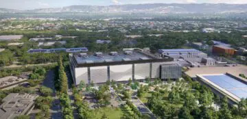 Aerial view of a modern data center surrounded by lush greenery with mountains in the background.