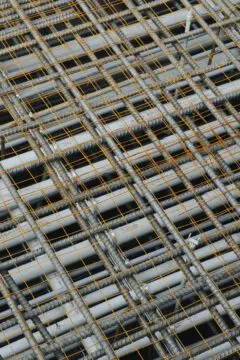 Grid of reinforced steel bars and orange wires for construction, showcasing industrial strength and stability.