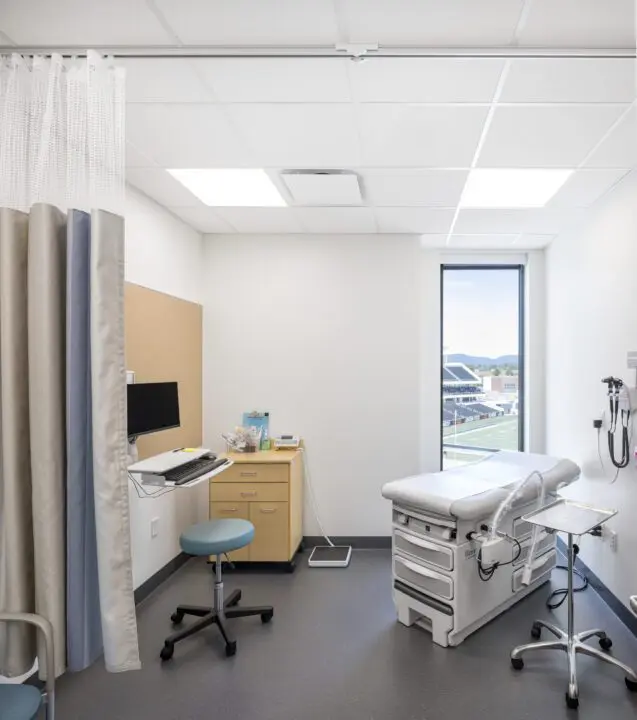 Modern healthcare clinic room with exam table, medical equipment, and window view. Clean and inviting medical office setting.