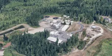 Aerial view of a wastewater treatment plant surrounded by lush green forest landscape.