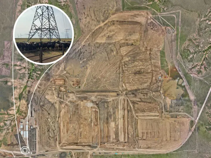 Aerial view of a cattle farm and surrounding landscape, featuring electricity pylons and wind turbines in the distance.