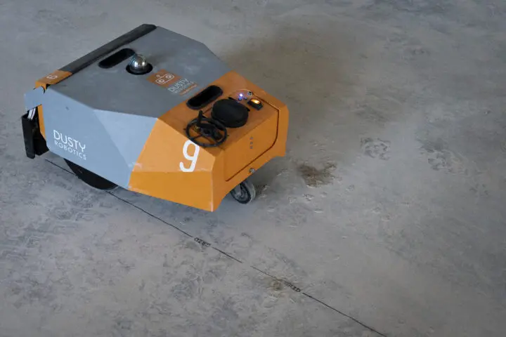 Orange and gray robotic device on a concrete surface.