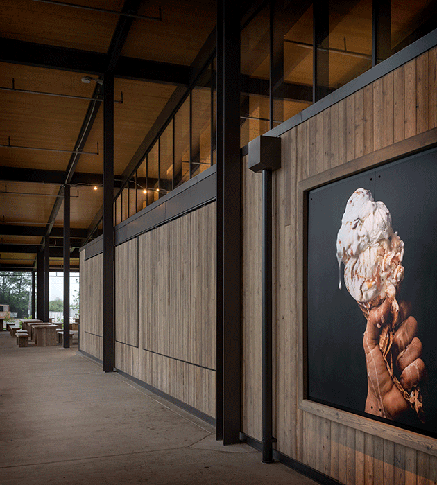 Exterior corridor with wooden walls, featuring a large poster of a hand holding a melting ice cream cone.
