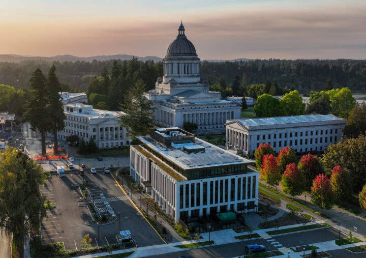 Aerial view of a grand government building surrounded by trees and additional structures at sunset. Tranquil, scenic atmosphere.